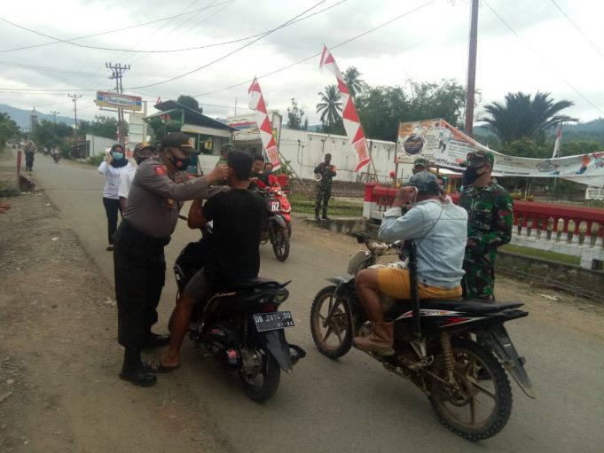 Polsek & Koramil Lolayan semakin perkuat soliditas dengan bersama-sama bagikan masker di jalan.